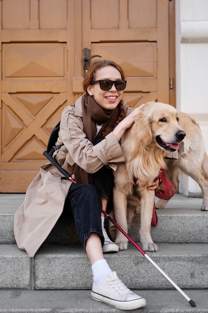 Foto gratuita mujer ciega sonriente con tiro completo de perro de servicio