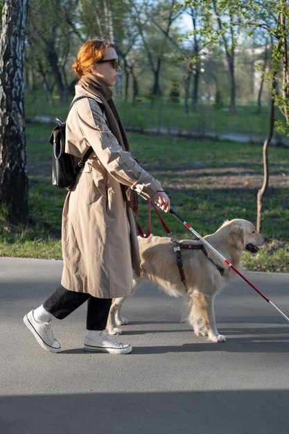 Mujer ciega de tiro completo caminando con perro y bastón