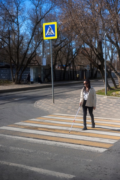 Mujer ciega de tiro completo en el cruce de peatones