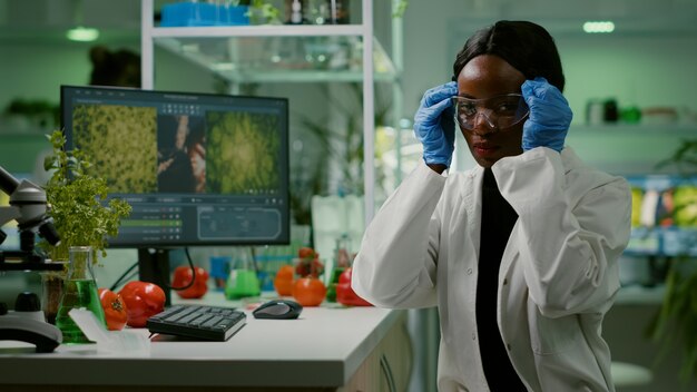 Mujer científica africana poniendo sus gafas médicas mirando a la cámara