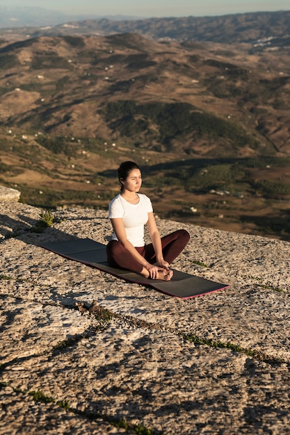 Foto gratuita mujer en la cima de la montaña meditando