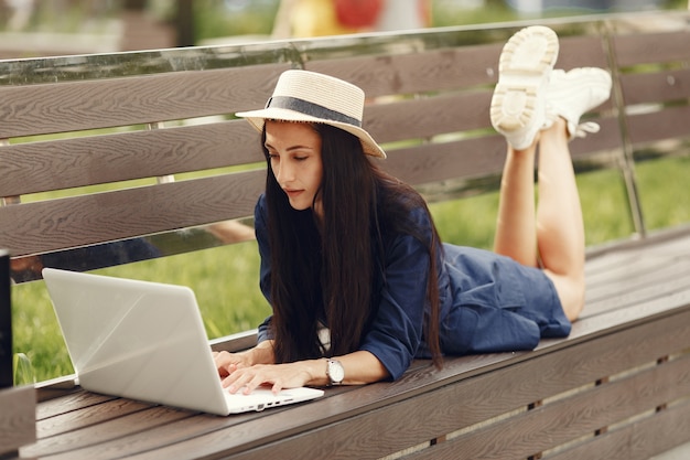 Mujer en una ciudad primaveral. Señora con una computadora portátil. Chica sentada en un banco.