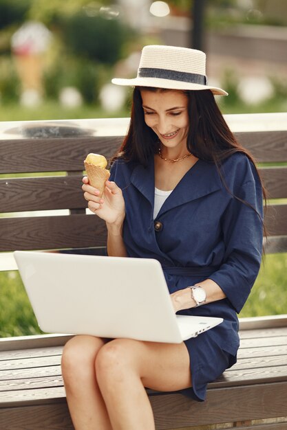 Mujer en una ciudad primaveral. Señora con una computadora portátil. Chica sentada en un banco.