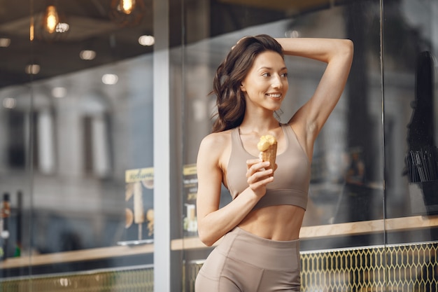 Mujer en una ciudad veraniega. Señora con helado. Morena por el edificio.