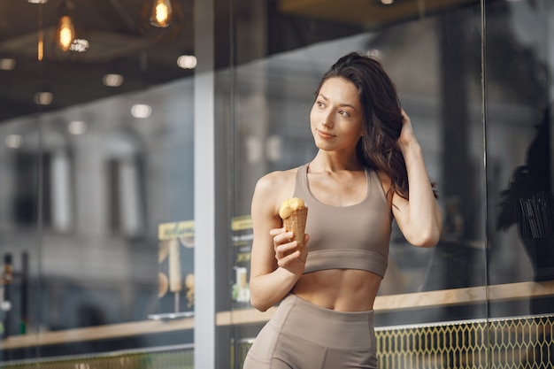 Mujer en una ciudad veraniega. Señora con helado. Morena por el edificio.