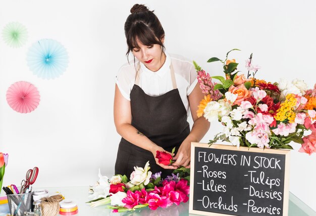 Mujer clasificando flores con pizarra en el escritorio de vidrio