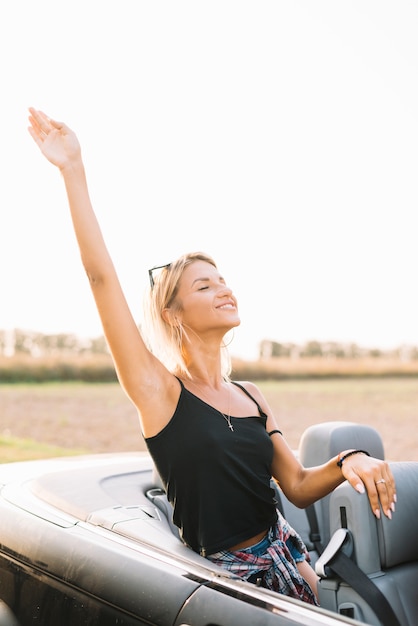 Foto gratuita mujer en coche con la mano arriba