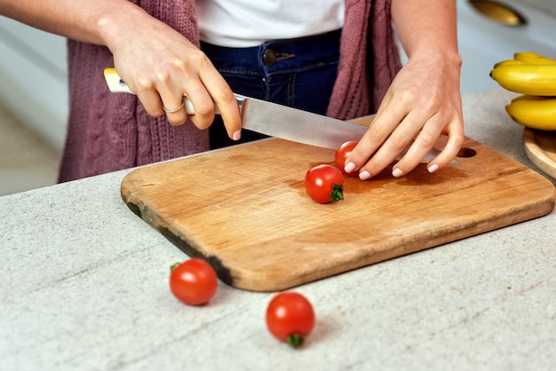 Una mujer en la cocina cortando tomates para ensalada