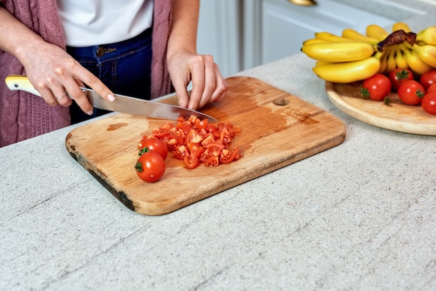 Una mujer en la cocina cortando tomates para ensalada