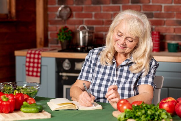 Mujer en la cocina escribiendo recetas