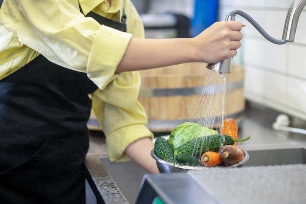 Mujer en la cocina lavando verduras antes de cocinar