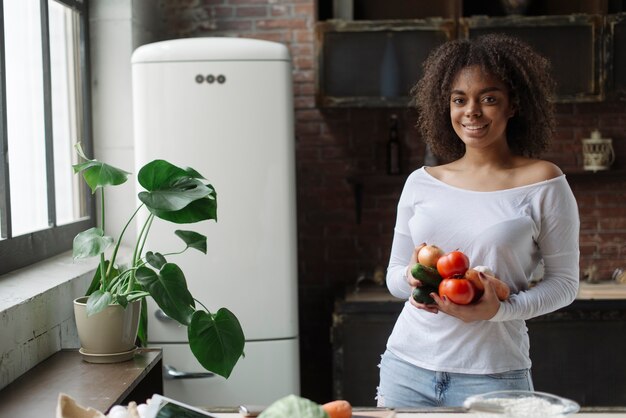 Mujer en cocina sujetando verduras