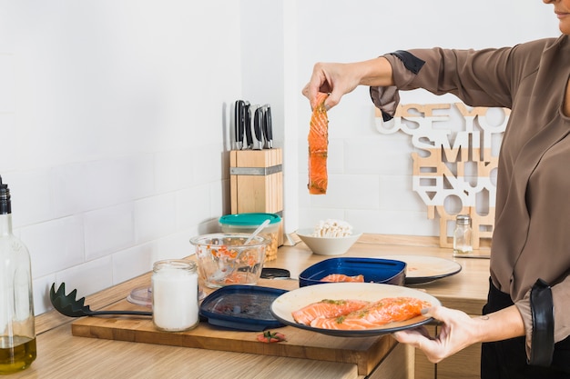 Mujer cocinando pescado en la cocina