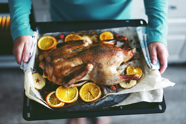 Foto gratuita mujer cocinar pato con verduras y ponerlo del horno.