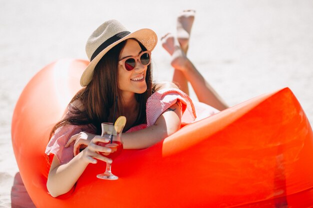 Mujer con coctail en el sombrero en la playa