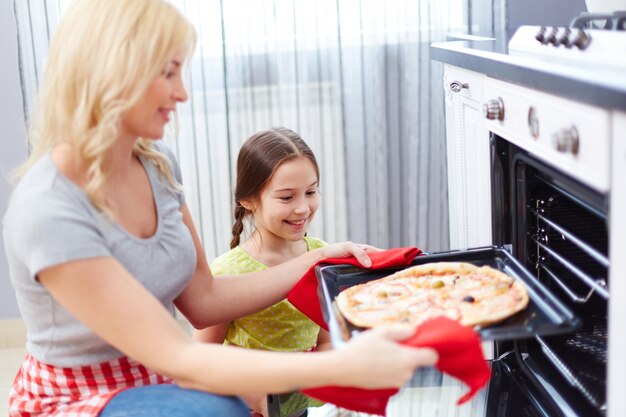 Mujer cogiendo la pizza del horno