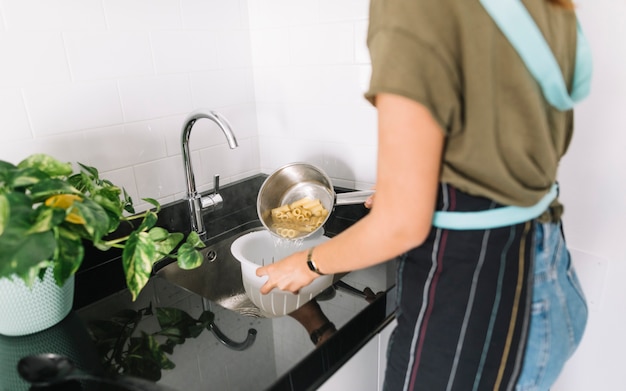 Mujer colar pasta hervida en el colador