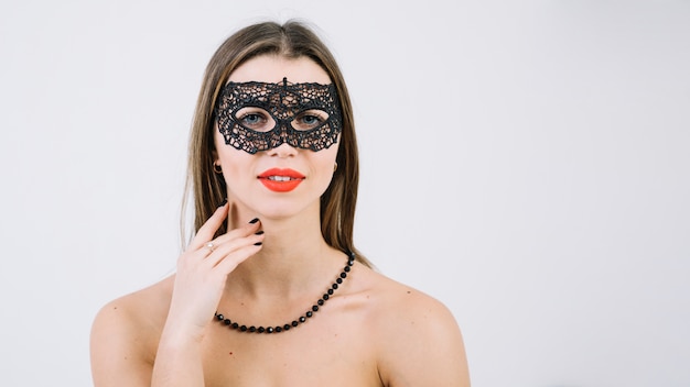 Mujer con collar de cuentas en mascarada máscara de carnaval mirando a cámara