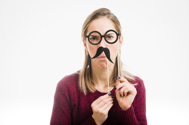 Mujer colocando bigote enfrente de cara