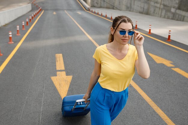 mujer con los colores de la bandera ucraniana en la carretera con maleta