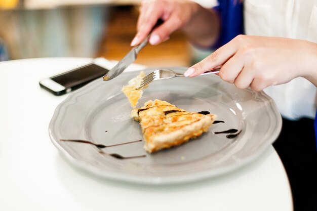 Mujer come un pastel en el café