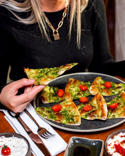 Mujer come pizza con verduras servidas con tomates cherry