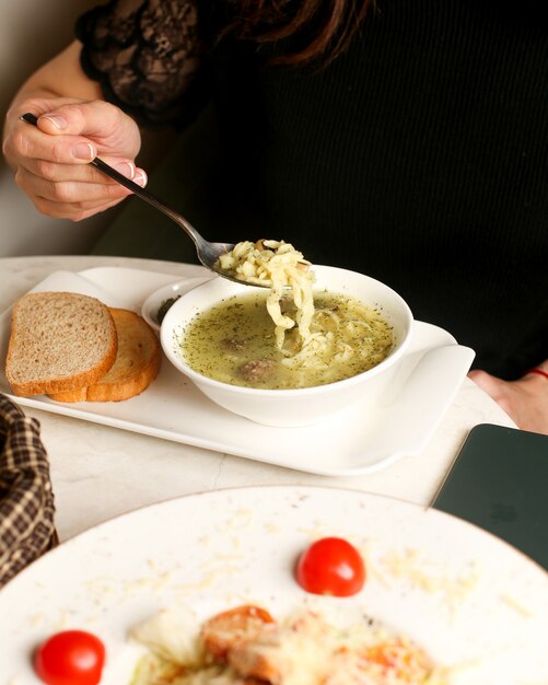 Mujer come sopa servida con hierbas secas