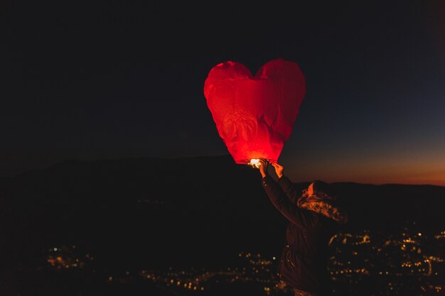 Mujer con una cometa de aire caliente por la noche