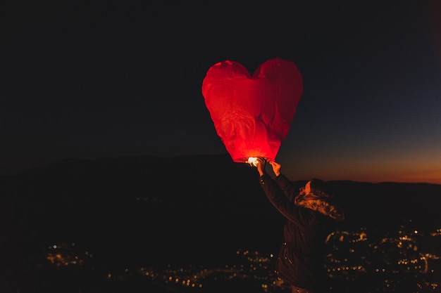 Mujer con una cometa de aire caliente por la noche