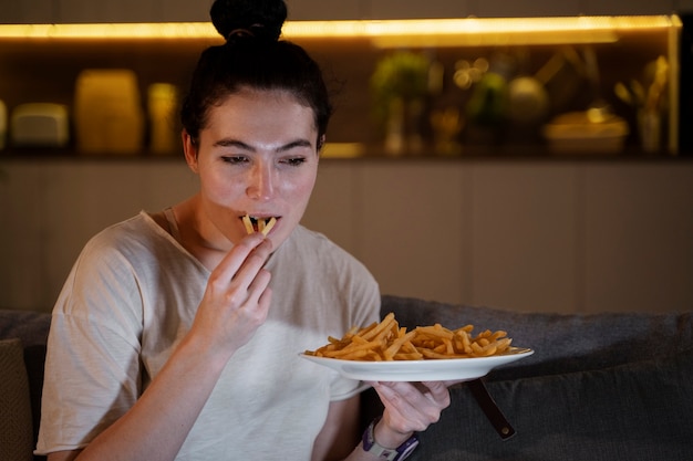 Mujer comiendo comida rápida mientras ve una película