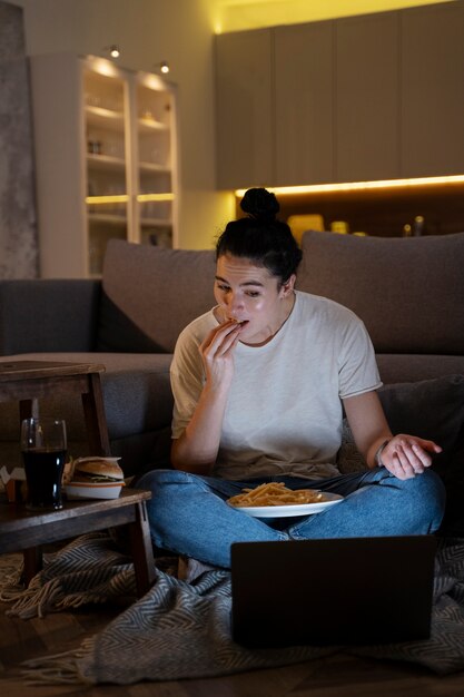 Mujer comiendo comida rápida mientras ve una película