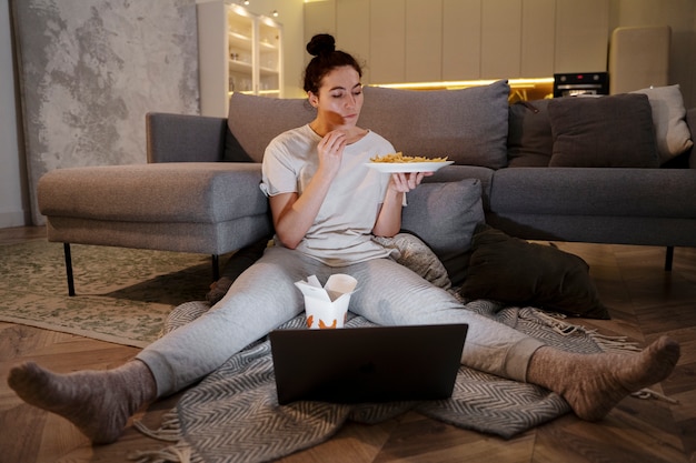 Mujer comiendo comida rápida mientras ve una película