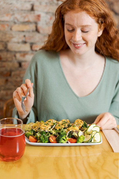 Mujer comiendo comida vegetariana tiro medio
