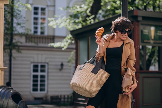 Mujer comiendo croissants fuera de la calle