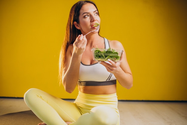 Foto gratuita mujer comiendo ensalada aislado sobre fondo amarillo