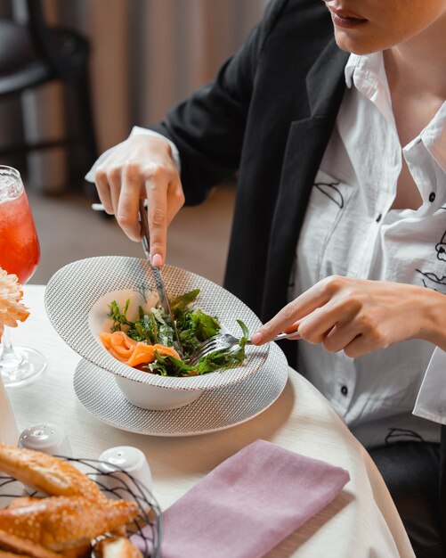 Mujer comiendo ensalada de salmón ahumado con rúcula y eneldo en el restaurante.