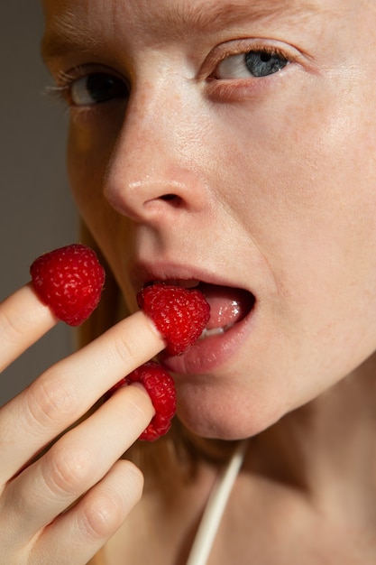 Mujer comiendo frambuesa fresca de cerca