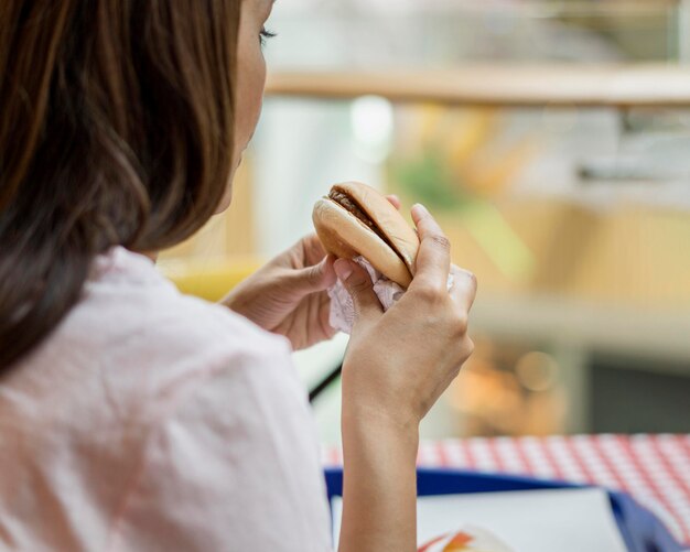 Mujer comiendo una hamburguesa en el restaurante