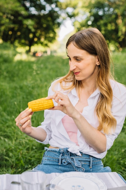 Foto gratuita mujer comiendo maíz en la naturaleza