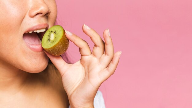 Mujer comiendo la mitad de la fruta de kiwi