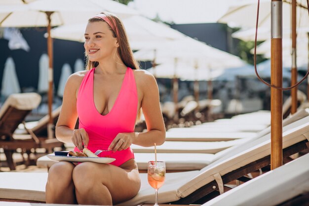 Mujer comiendo nalysnyki ucraniano junto a la piscina