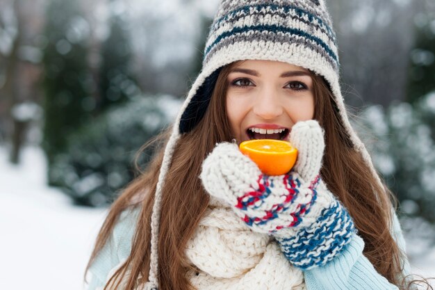 Mujer comiendo naranja durante el invierno