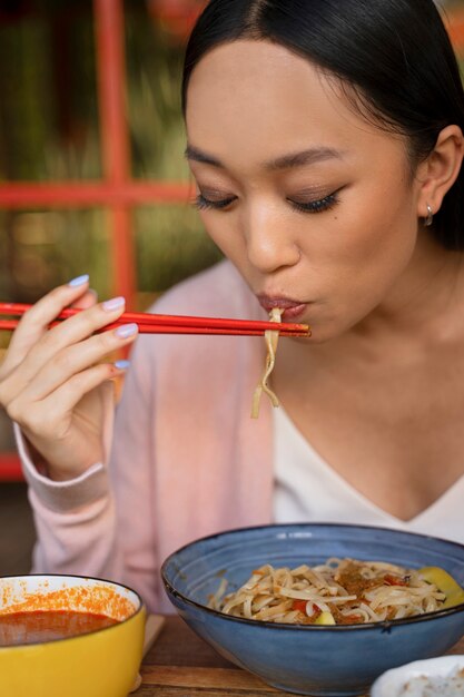 Mujer comiendo con palillos vista frontal