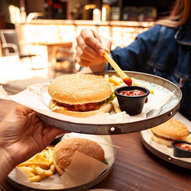 Mujer comiendo papas fritas con salsa de tomate