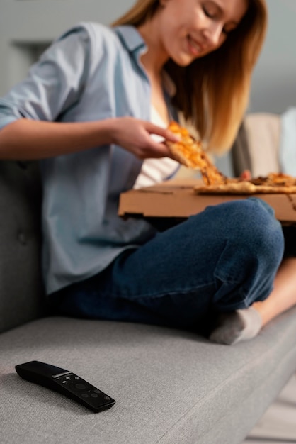 Mujer comiendo pizza mientras ve la televisión de cerca