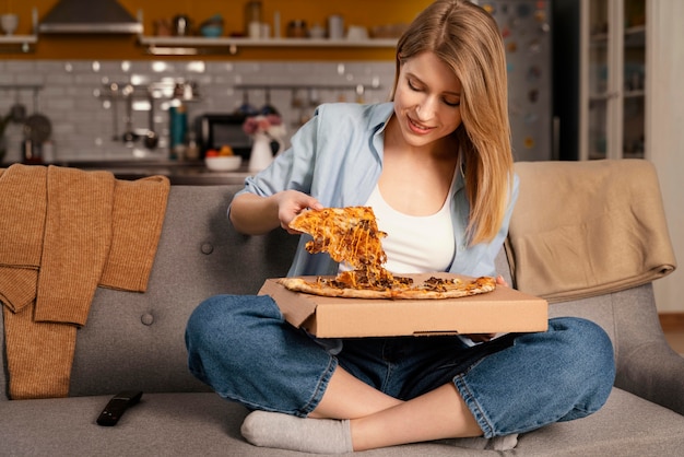 Mujer comiendo pizza mientras ve la televisión