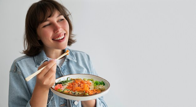 Mujer comiendo un plato de mariscos con salmón