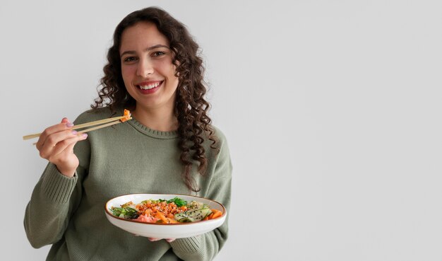 Mujer comiendo plato de mariscos con salmón