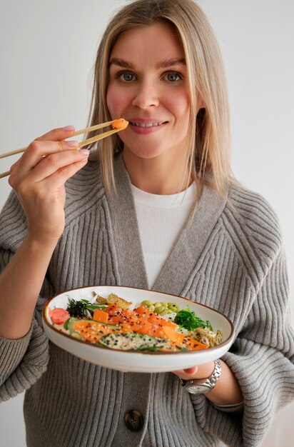 Mujer comiendo un plato de mariscos con salmón