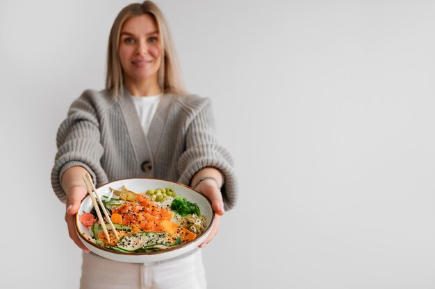 Mujer comiendo plato de mariscos con salmón